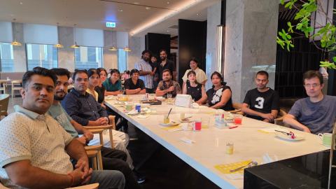 Lab members at a long white table in a restaurant, turning towards the camera during the meal.