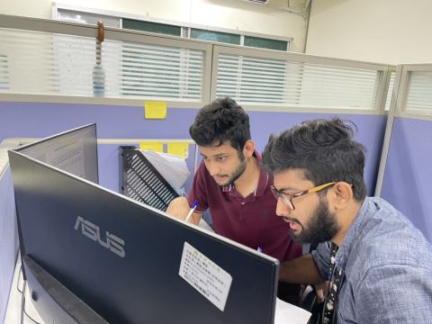 Two lab members discussing work at a computer.