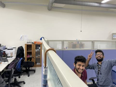 Two lab members waving from their workstations.