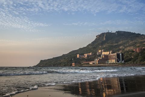 The beach and hillside campus buildings at dusk.