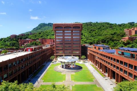 Aerial view of NSYSU campus buildings around a courtyard, with green hills behind.